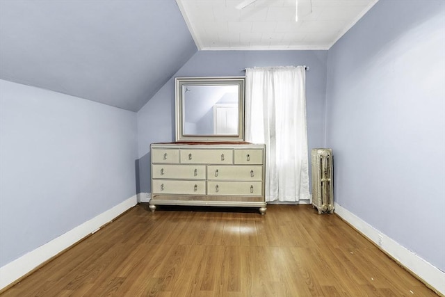 additional living space with vaulted ceiling, wood finished floors, baseboards, and radiator heating unit