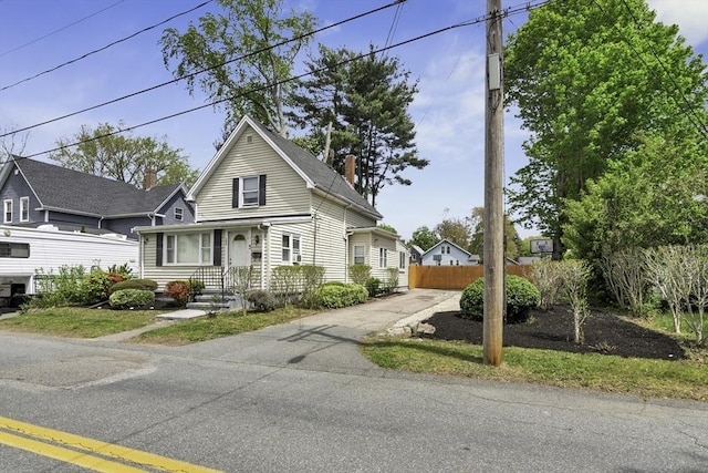 view of front of home with a chimney, driveway, and fence