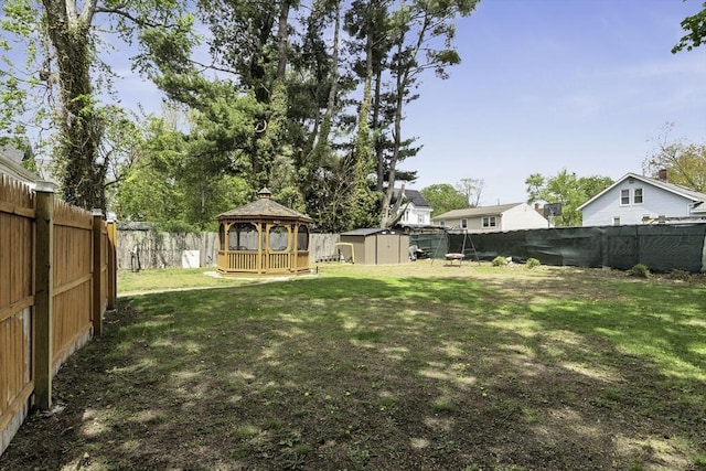 view of yard featuring an outdoor structure, a gazebo, a fenced backyard, and a shed