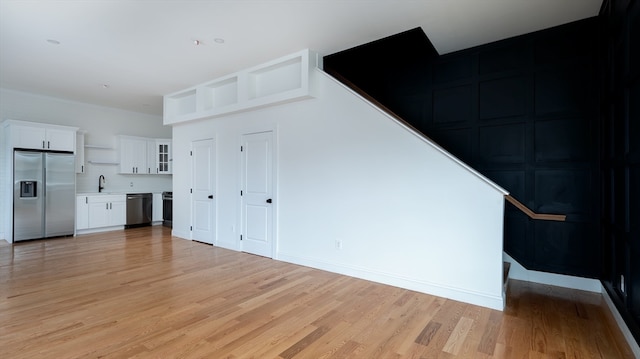 unfurnished living room featuring sink and light hardwood / wood-style floors