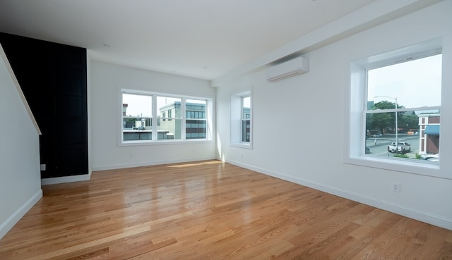 empty room with light hardwood / wood-style floors and an AC wall unit