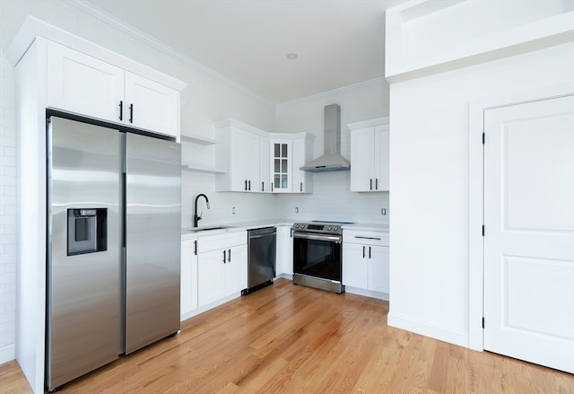 kitchen featuring stainless steel appliances, light wood-type flooring, wall chimney exhaust hood, and white cabinetry