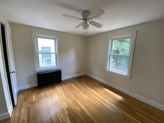 295 Atlantic, Quincy, MA 02171 - empty room with radiator heating unit, light wood-style flooring, and ceiling fan