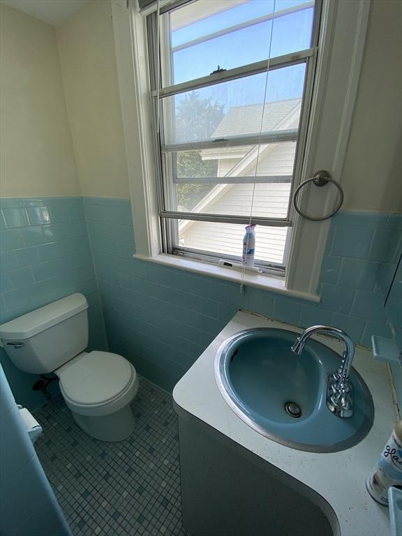295 Atlantic, Quincy, MA 02171 - bathroom featuring tile walls, vanity, wainscoting, and tile patterned floors