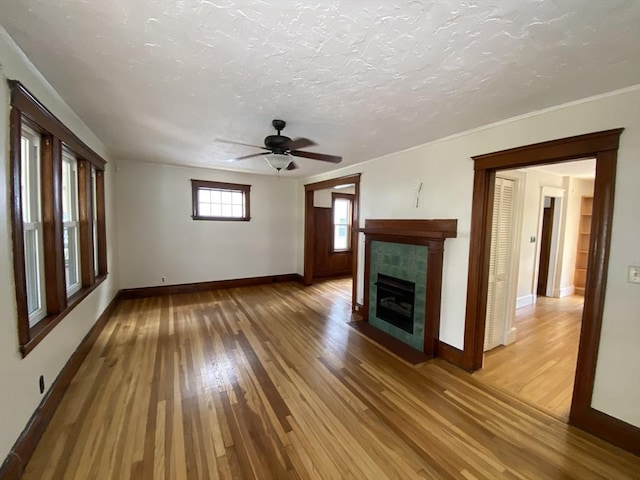 295 Atlantic, Quincy, MA 02171 - unfurnished living room featuring light wood-style flooring, a ceiling fan, a fireplace, a textured ceiling, and ornamental molding