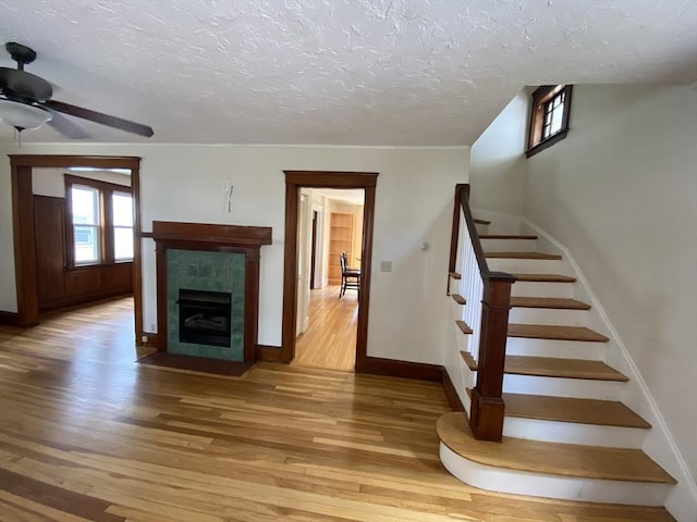 295 Atlantic, Quincy, MA 02171 - unfurnished living room featuring light wood-style floors, a textured ceiling, stairway, a ceiling fan, and a fireplace