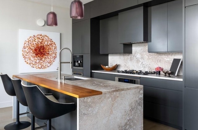 kitchen featuring gray cabinets, sink, wall chimney range hood, and decorative backsplash