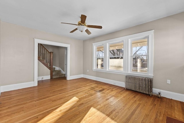 empty room with ceiling fan, radiator heating unit, and light wood-type flooring