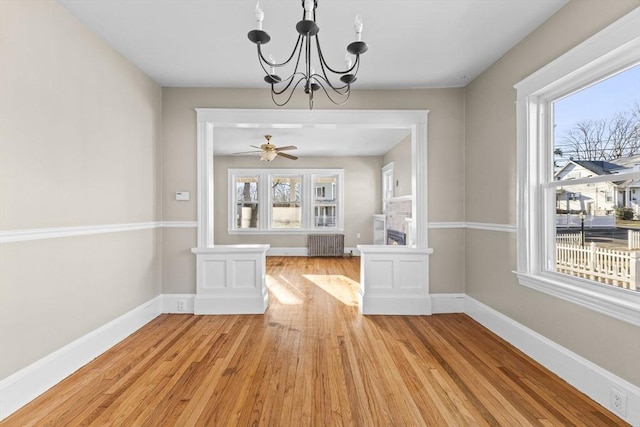 unfurnished dining area featuring radiator, ceiling fan with notable chandelier, and light hardwood / wood-style flooring