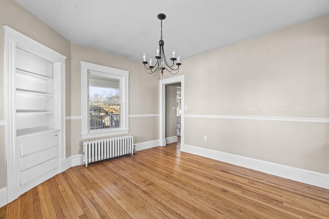 unfurnished dining area with hardwood / wood-style flooring, radiator, and a notable chandelier