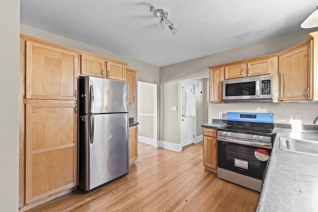 kitchen featuring stainless steel appliances, sink, light brown cabinets, and light hardwood / wood-style flooring