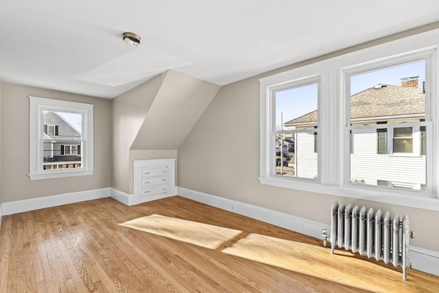 additional living space featuring lofted ceiling, hardwood / wood-style flooring, and radiator heating unit