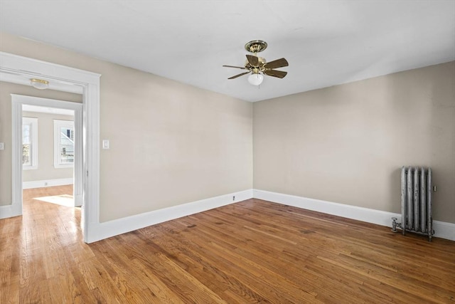 spare room with hardwood / wood-style flooring, radiator heating unit, and ceiling fan