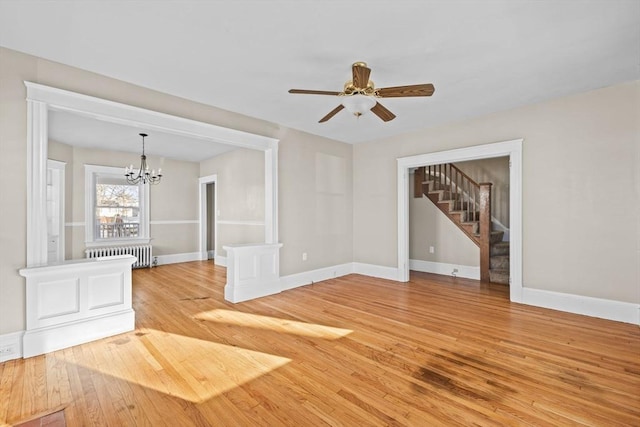 unfurnished living room featuring radiator, ceiling fan with notable chandelier, and light wood-type flooring