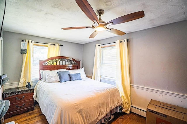 214 Hovenden Ave, Brockton, MA 02302 - bedroom featuring a baseboard heating unit, multiple windows, dark wood finished floors, and ceiling fan