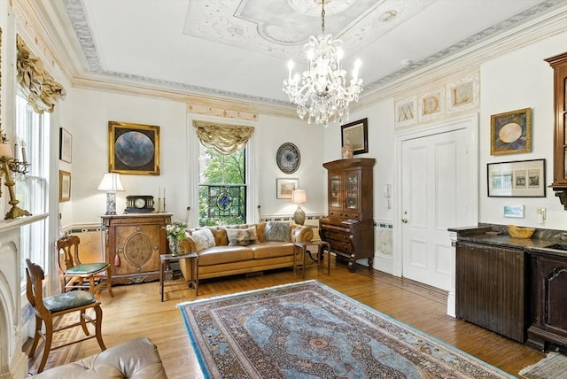 338 Harvard St Unit 1, Cambridge, MA 02139 - sitting room with light wood-style floors, a tray ceiling, a chandelier, ornamental molding, and a wainscoted wall