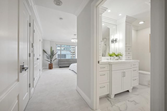 ensuite bathroom with toilet, vanity, ornamental molding, marble finish floor, and ensuite bath