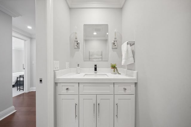 bathroom featuring wood finished floors, recessed lighting, crown molding, baseboards, and vanity