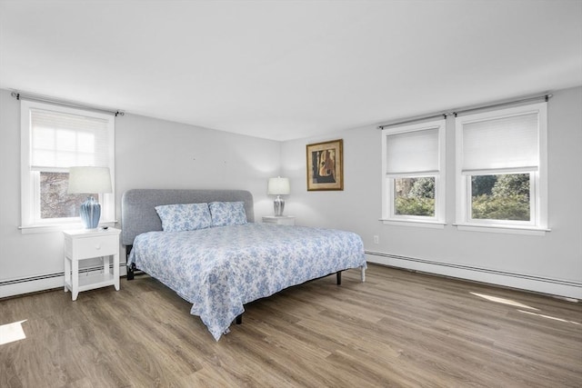 bedroom with baseboard heating and wood finished floors