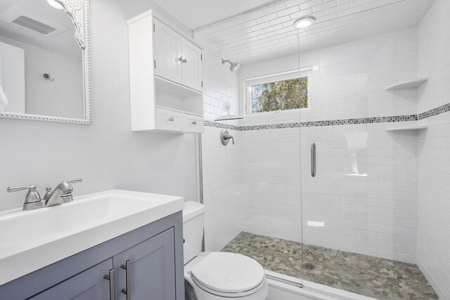 bathroom featuring toilet, vanity, a shower stall, and visible vents