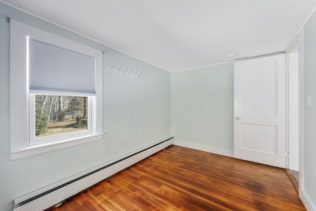 empty room with baseboard heating, wood finished floors, and baseboards