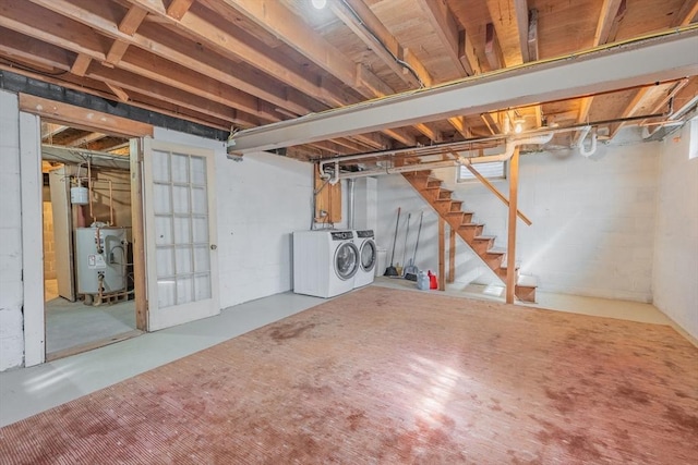 unfinished basement with washing machine and dryer, water heater, and stairway