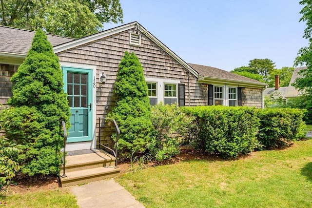 view of front of house with entry steps, a shingled roof, and a front yard