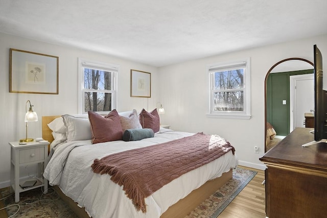 bedroom with multiple windows and light wood-type flooring