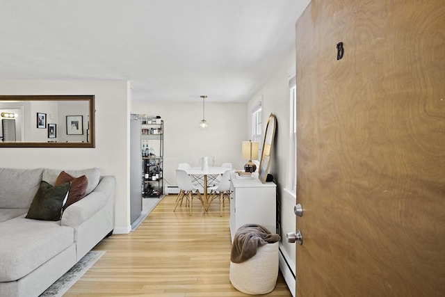 living room with a baseboard heating unit and wood-type flooring