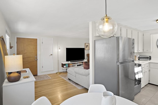 kitchen with light tile patterned flooring, stainless steel appliances, hanging light fixtures, and white cabinets