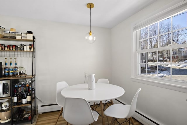 dining space featuring a baseboard heating unit, hardwood / wood-style floors, and bar area