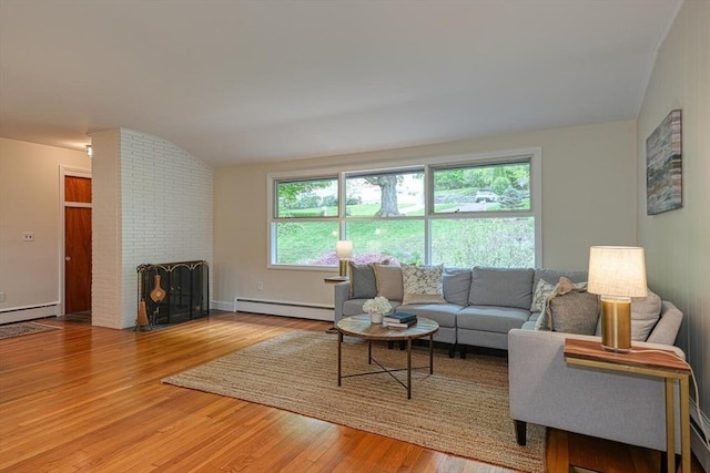 living room featuring a baseboard heating unit, baseboard heating, wood finished floors, and a fireplace