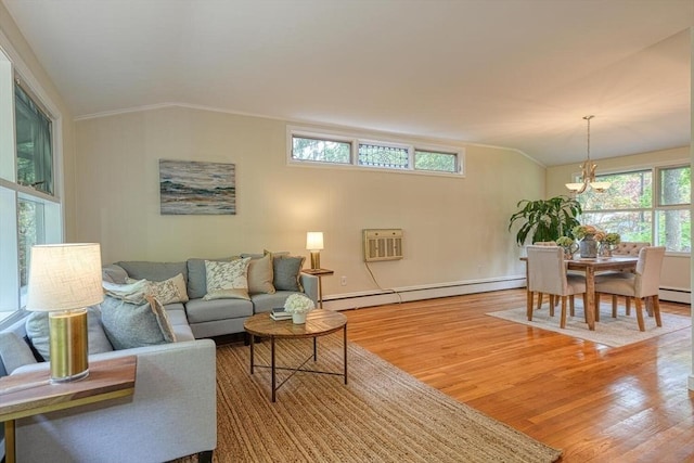 living area featuring a baseboard heating unit, lofted ceiling, wood finished floors, a chandelier, and baseboards