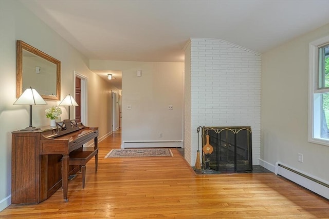 hall with baseboard heating, a baseboard heating unit, light wood finished floors, baseboards, and vaulted ceiling