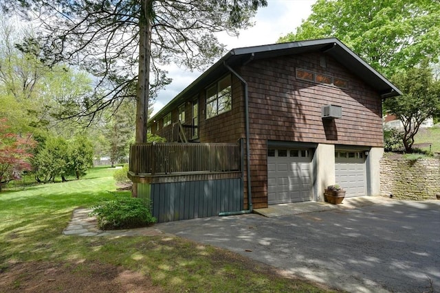 view of home's exterior featuring asphalt driveway, an attached garage, a yard, and a wall mounted air conditioner