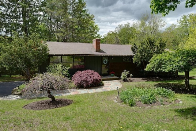 ranch-style home with a front yard and a chimney