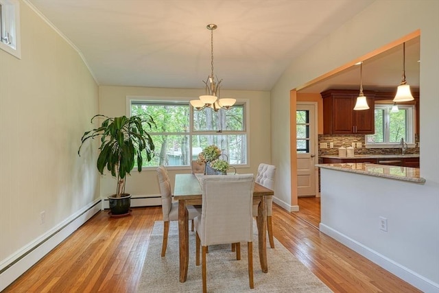 dining room featuring baseboard heating, light wood-type flooring, a chandelier, baseboards, and crown molding