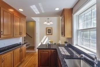 kitchen featuring sink, decorative light fixtures, light hardwood / wood-style floors, kitchen peninsula, and a chandelier