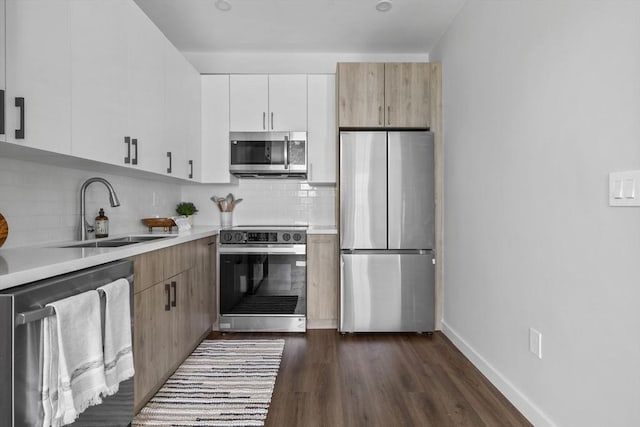 kitchen with a sink, dark wood finished floors, appliances with stainless steel finishes, and light countertops