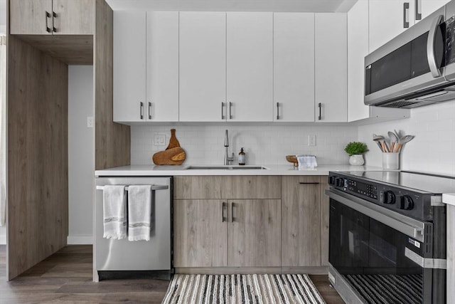 kitchen featuring light countertops, tasteful backsplash, a sink, dark wood finished floors, and stainless steel appliances