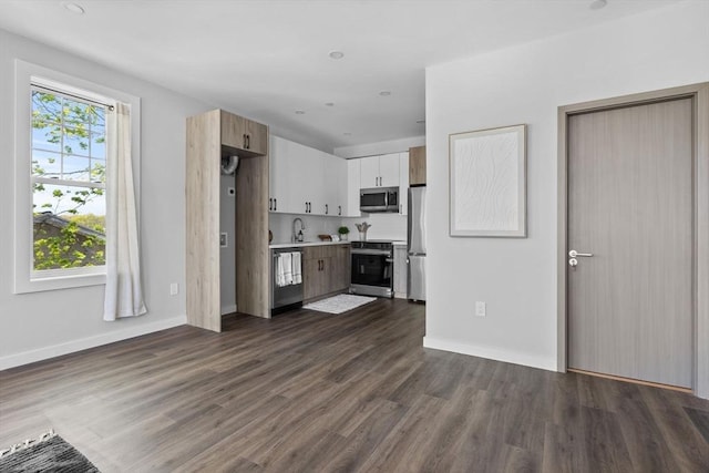 kitchen with light countertops, appliances with stainless steel finishes, white cabinetry, and dark wood-type flooring