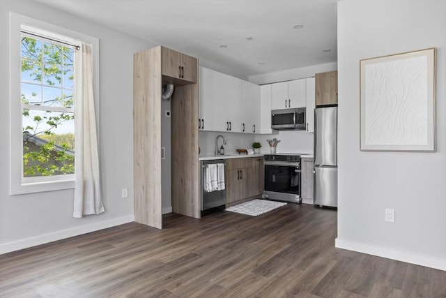 kitchen featuring light countertops, baseboards, stainless steel appliances, and dark wood-style flooring