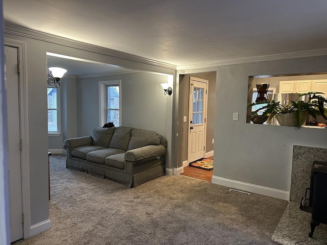 living area with baseboards, visible vents, carpet, and crown molding