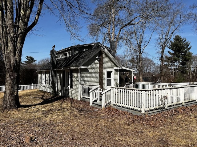 view of property exterior featuring fence, a chimney, and a deck