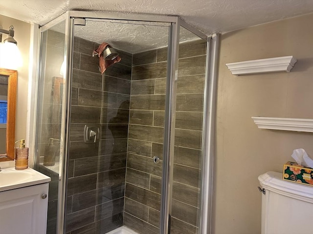 bathroom featuring toilet, vanity, a stall shower, and a textured ceiling