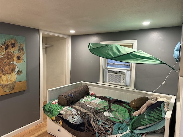 bedroom featuring baseboards, wood finished floors, recessed lighting, and cooling unit