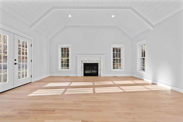 unfurnished living room with a healthy amount of sunlight, light wood-type flooring, and french doors