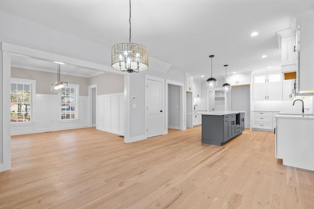 kitchen featuring a center island, sink, hanging light fixtures, light hardwood / wood-style floors, and white cabinets