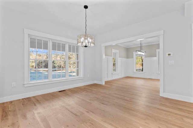 unfurnished dining area featuring a notable chandelier, a wealth of natural light, and light hardwood / wood-style flooring