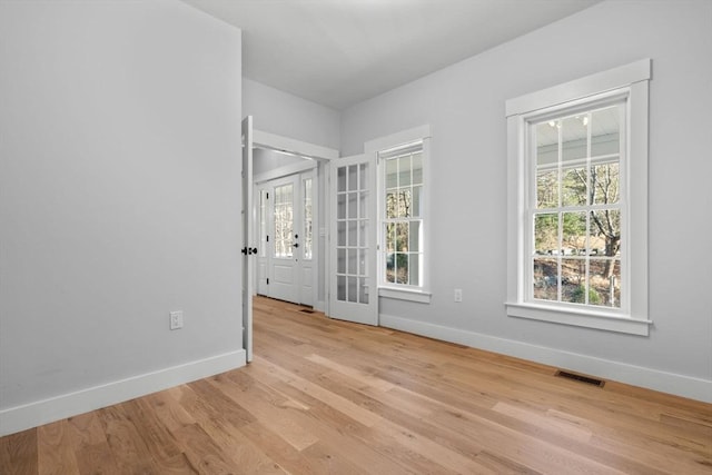 unfurnished room with french doors and light hardwood / wood-style flooring